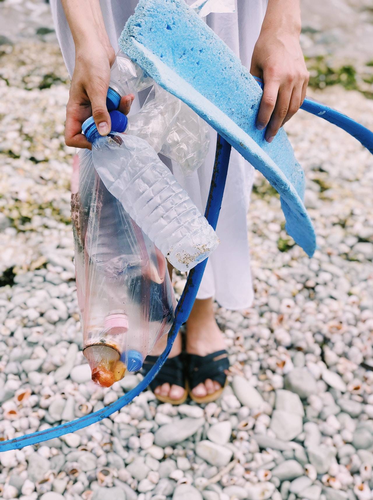 Person holds out washed-up plastic rubbish on a beach 