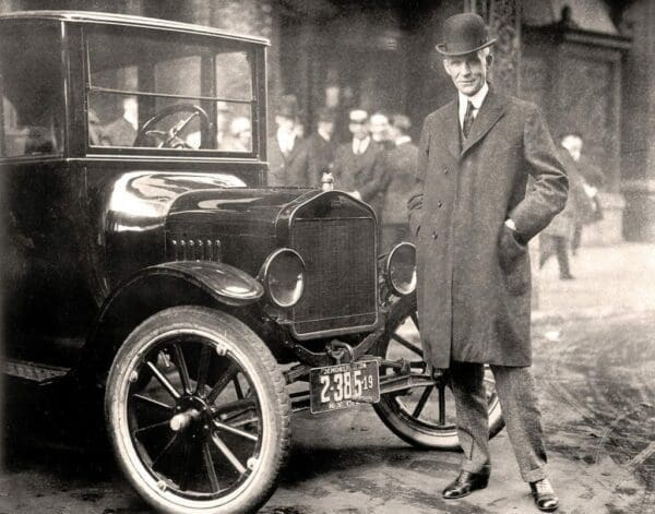 Black and white photo Henry Ford 1921 in suit beside a classic car in the middle of the street