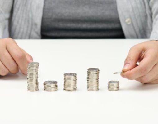 Woman hand creating piles of silver coins represent cost