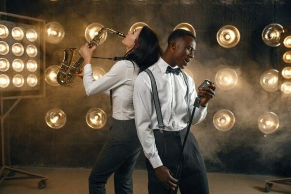 Male jazz performer and female saxophonist performing on stage with bright lights