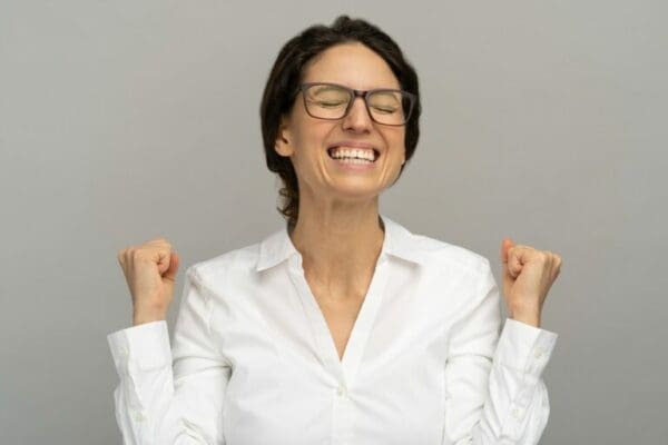 Female leader manager celebrating success with fists clenched and grey background