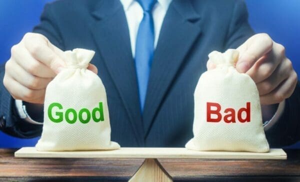 Businessman holding good and bad money bags on a balanced scale to represent strength and weakness