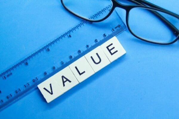 glasses, ruler and white cubes spelling value on blue surface