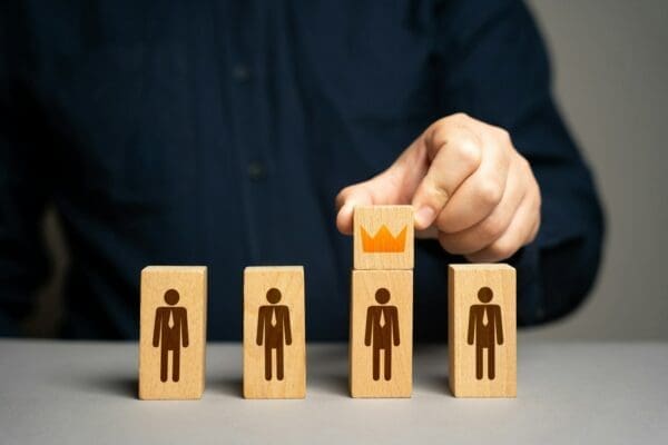 person putting a crown on leader wooden figure