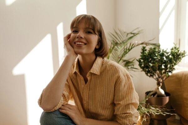 Smilling young woman with green plants in the background